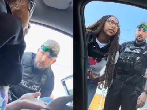 Police officers speak with a couple beside a car in a parking lot.
