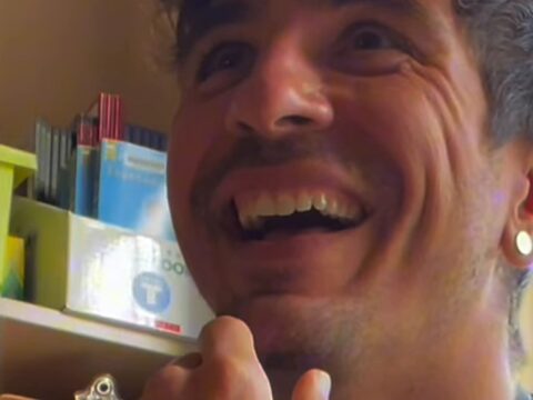 Teacher Damien Fagiolino laughing in his classroom as his students sing his band's song back to him