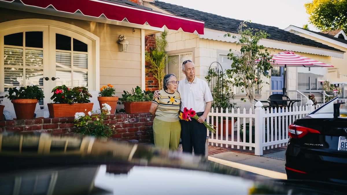 Older couple standing in front of their home